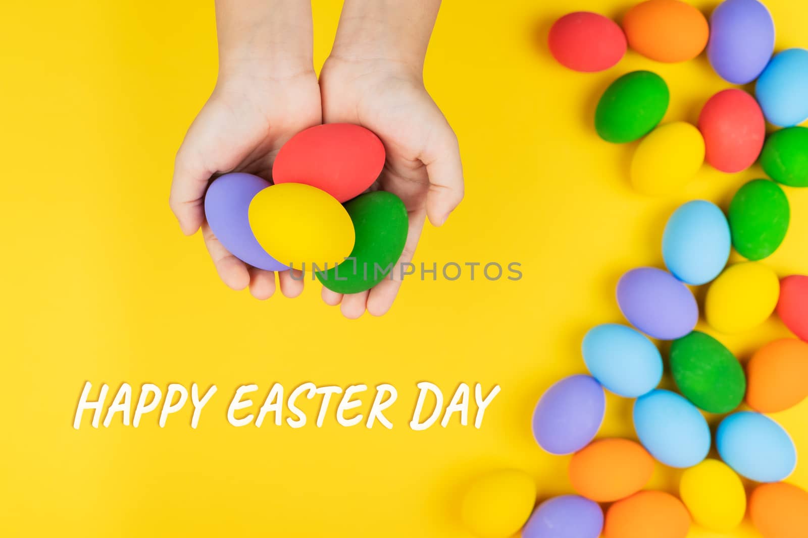 Easter day with decorated eggs in child hand on yellow background