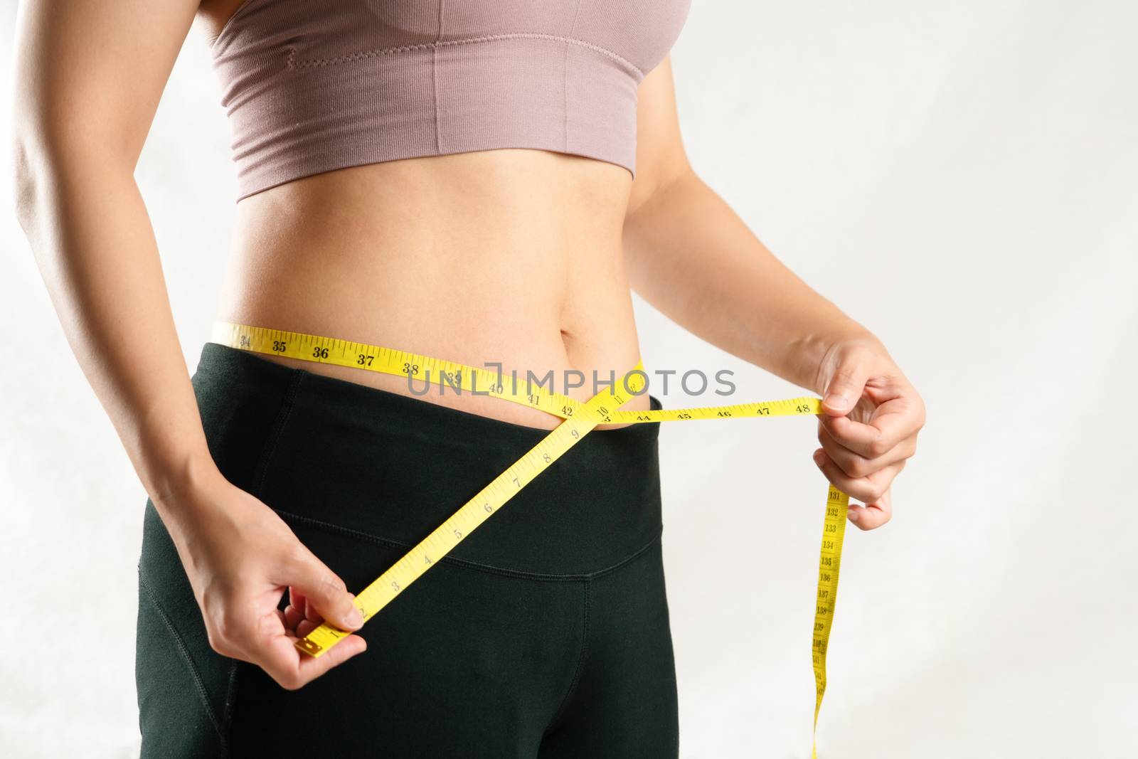 young woman measuring her belly waist with measure tape, woman diet lifestyle concept