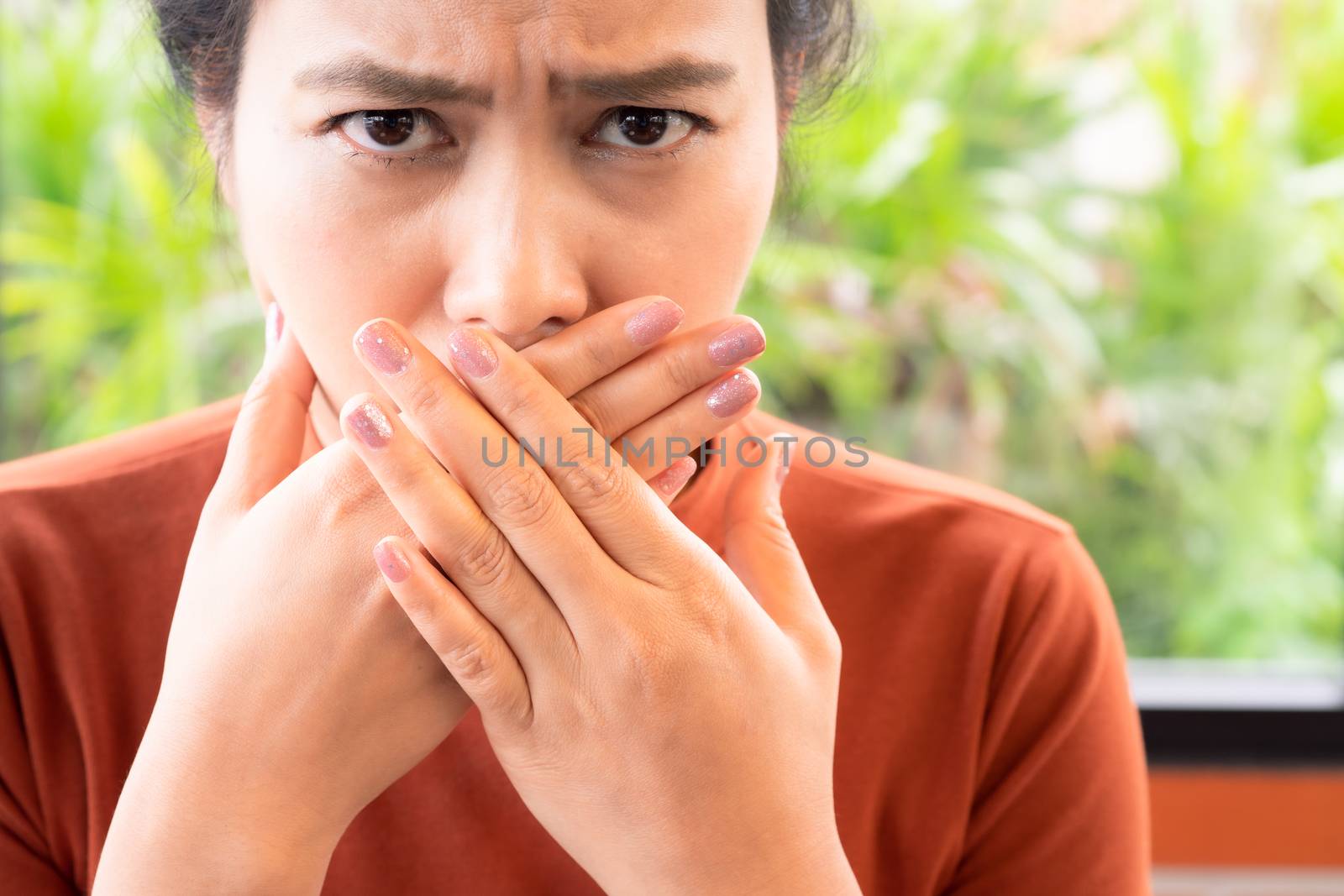 Woman with bad breath covering mouth, halitosis concept by psodaz