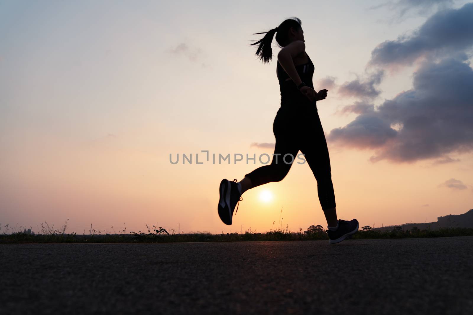 sport woman running on a road. Fitness woman training at sunset by psodaz