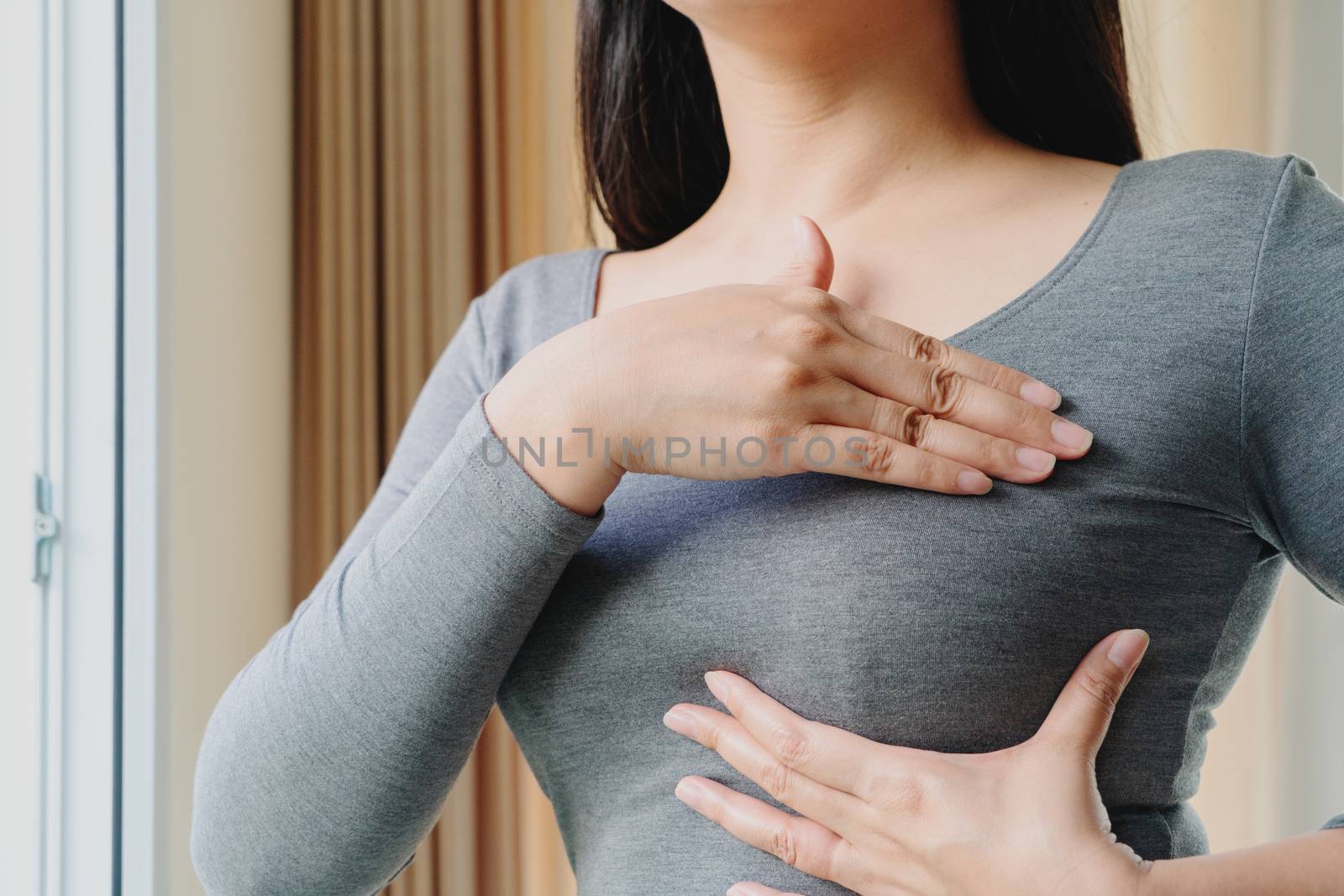 Woman hand checking lumps on her breast for signs of breast cancer. Women healthcare concept.