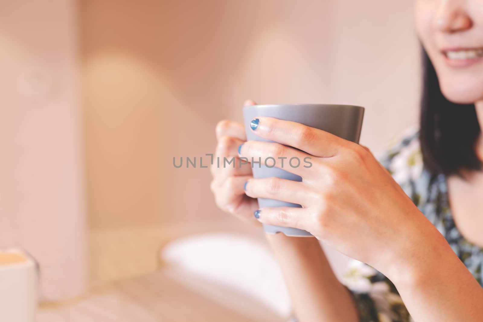 hands holding hot cup of coffee or tea in morning sunlight