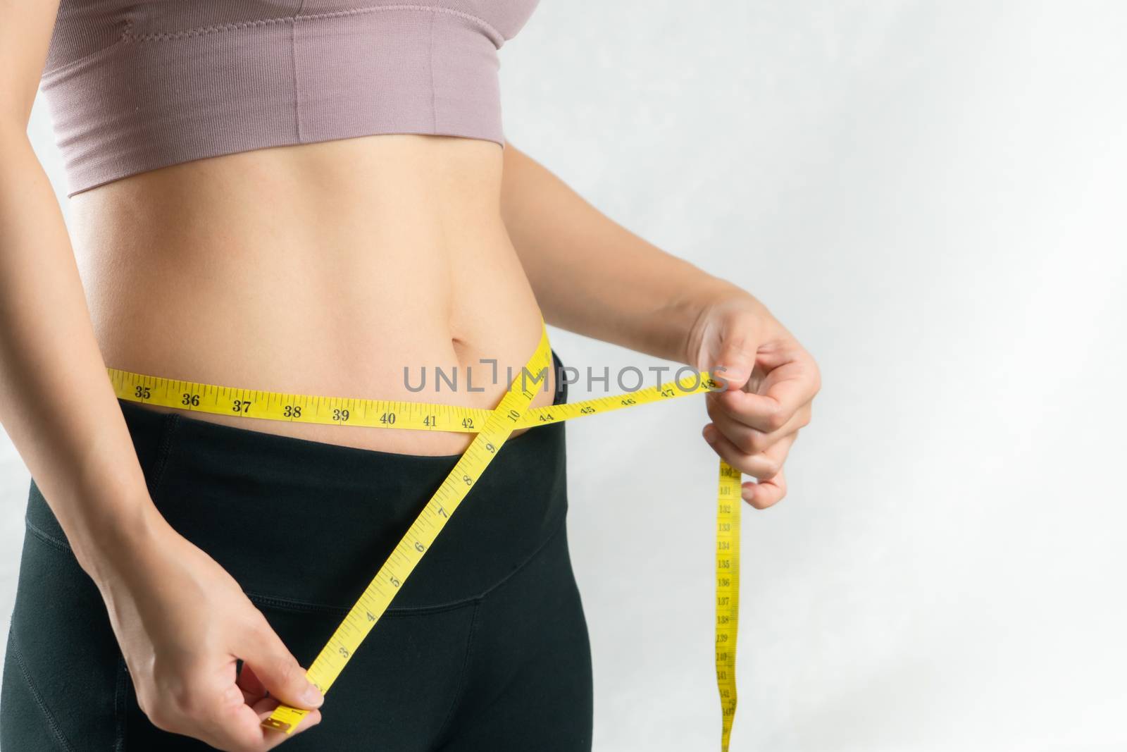 young woman measuring her belly waist with measure tape, woman diet lifestyle concept