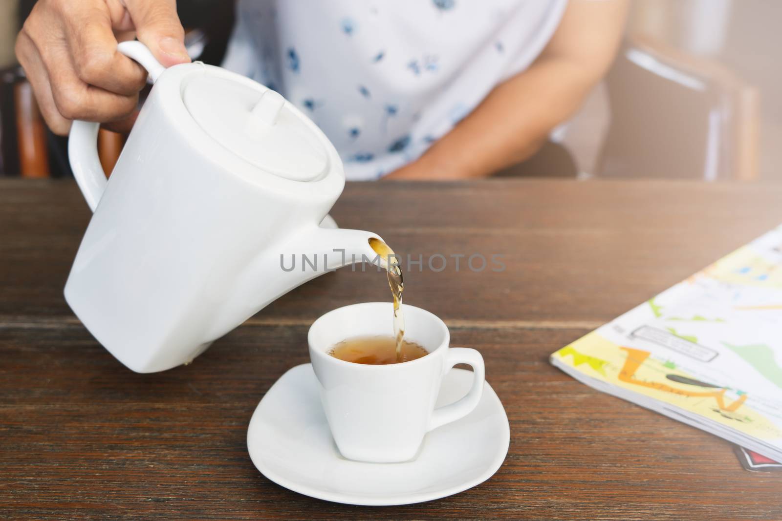 top view of a female pouring tea on wooden table