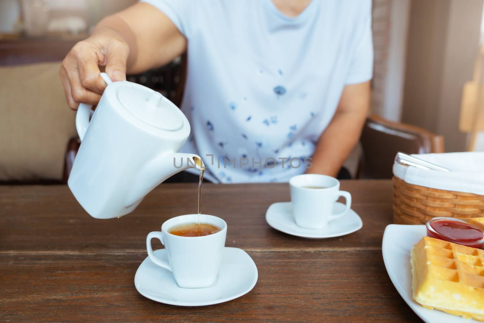 top view of a female pouring tea on wooden table by psodaz