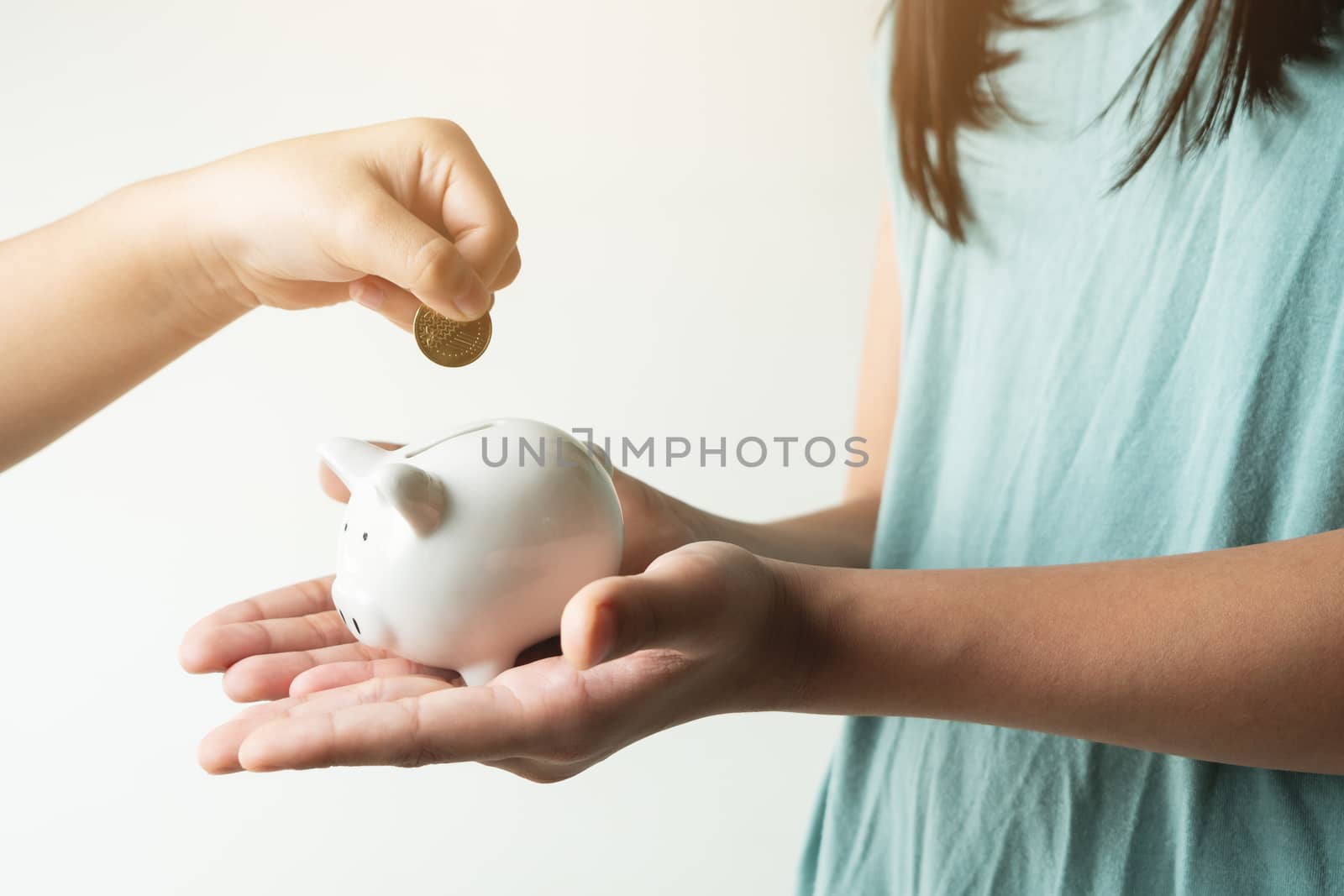 Saving and business concept, two little girl with piggy bank and coins at home