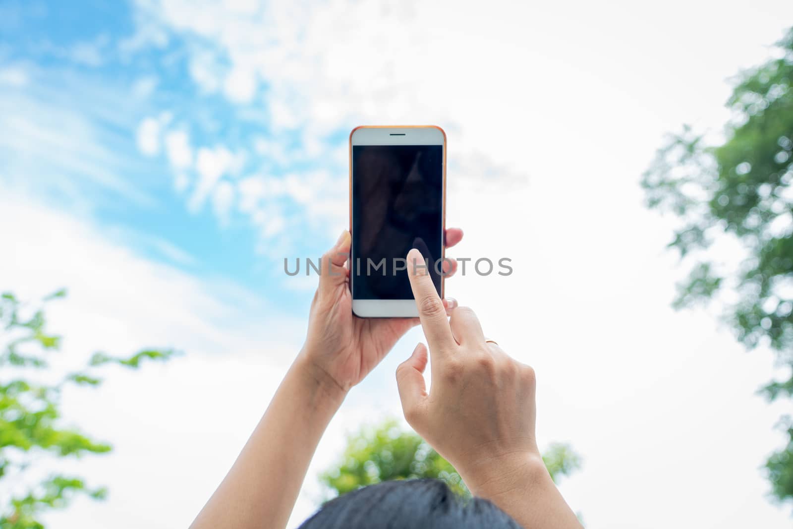 woman holding smartphone with blurred sky background