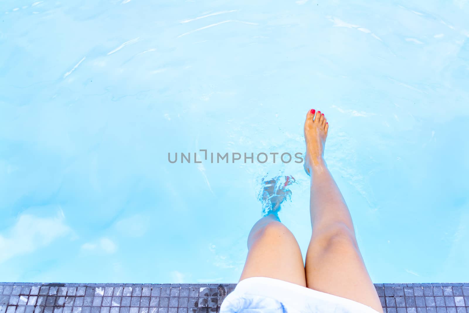 Girl legs in the blue swimming pool,   Summer holiday concept. by psodaz