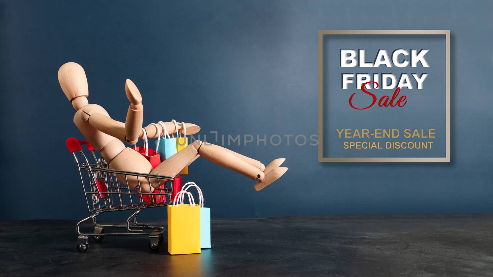 Black Friday sale, wooden doll sitting on shopping cart with sho by psodaz