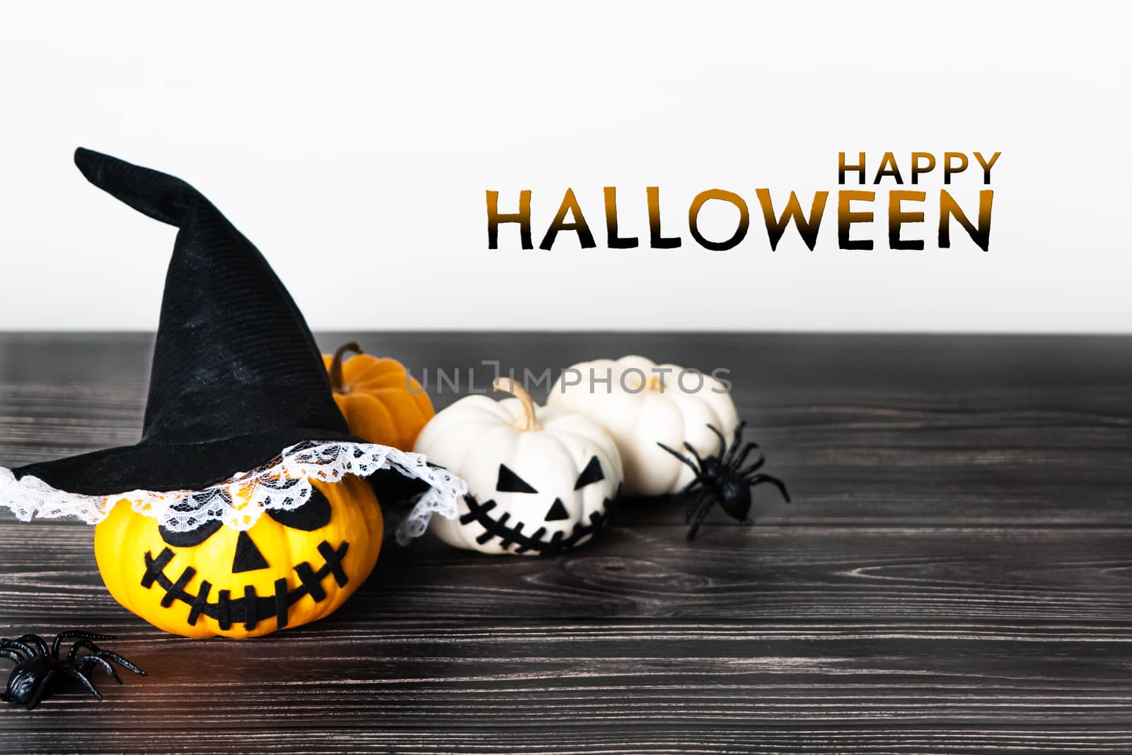 Happy Halloween, horror pumpkin and scary spider on wooden table