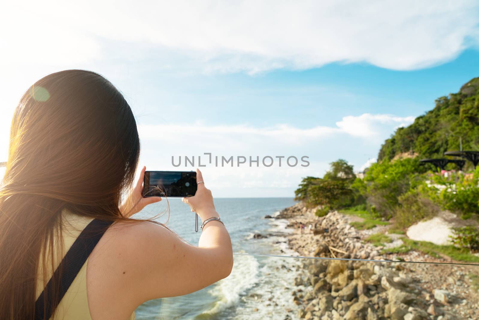 Travel lifestyle. Female tourist taking photo of beautiful beach on smartphone
