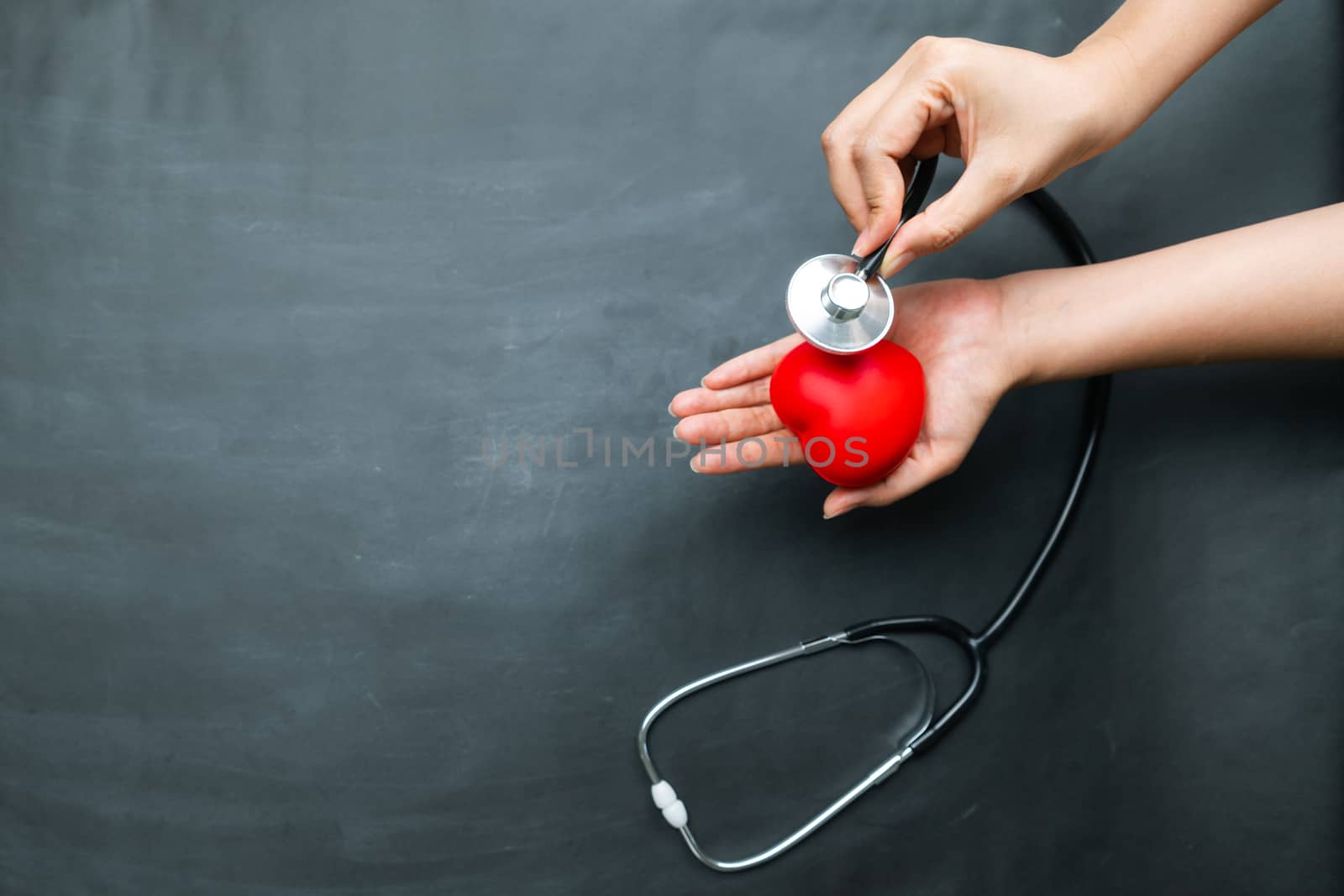 World heart day concept of young woman hand holding red heart and stethoscope