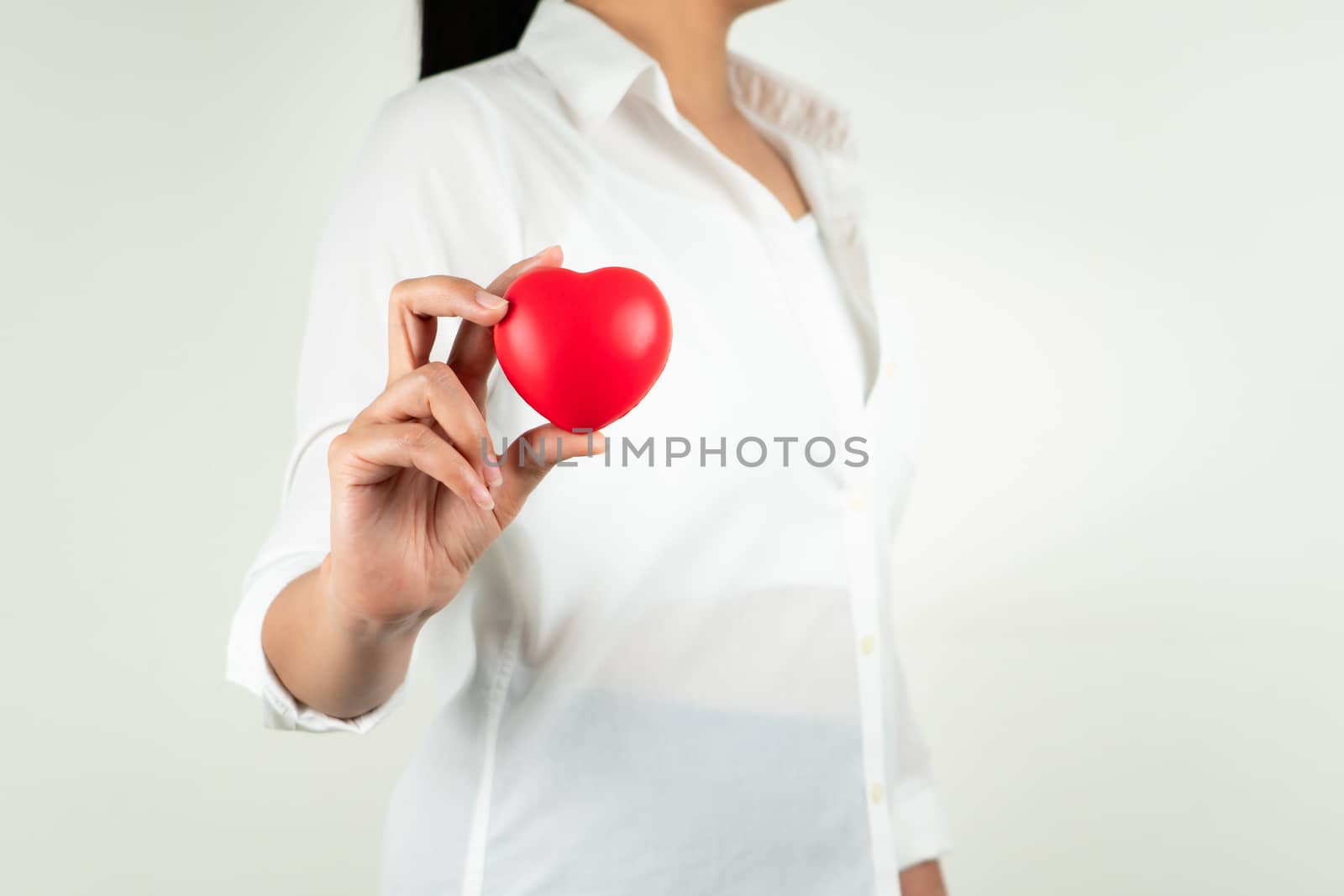 World heart day concept of young woman hand holding red heart by psodaz