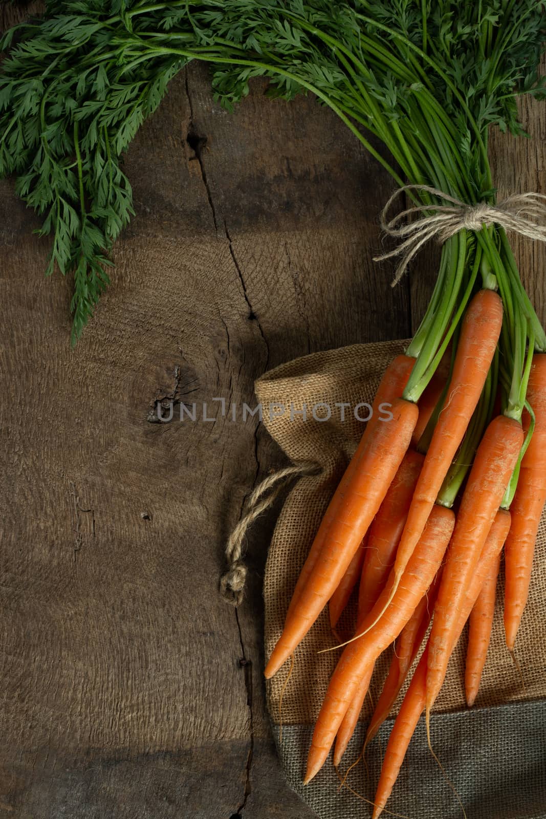 Fresh organic carrots with canvas on antique wooden table. Rustic kitchen concept. Banner, poster, mock up. Grunge, vintage, rustic style