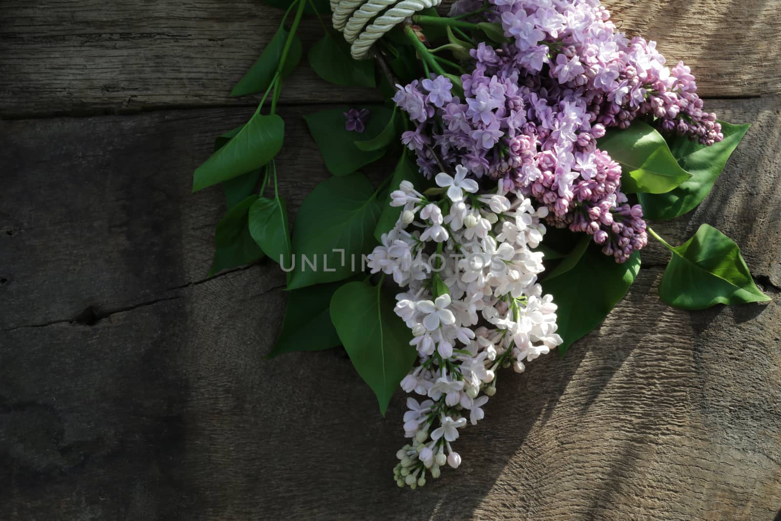 Happy mothers day beautiful purple spring flowers with gift tag. Lilac flowers on old antique brown wood rustic background. Top view, flat lay. Banner, card, poster concept.