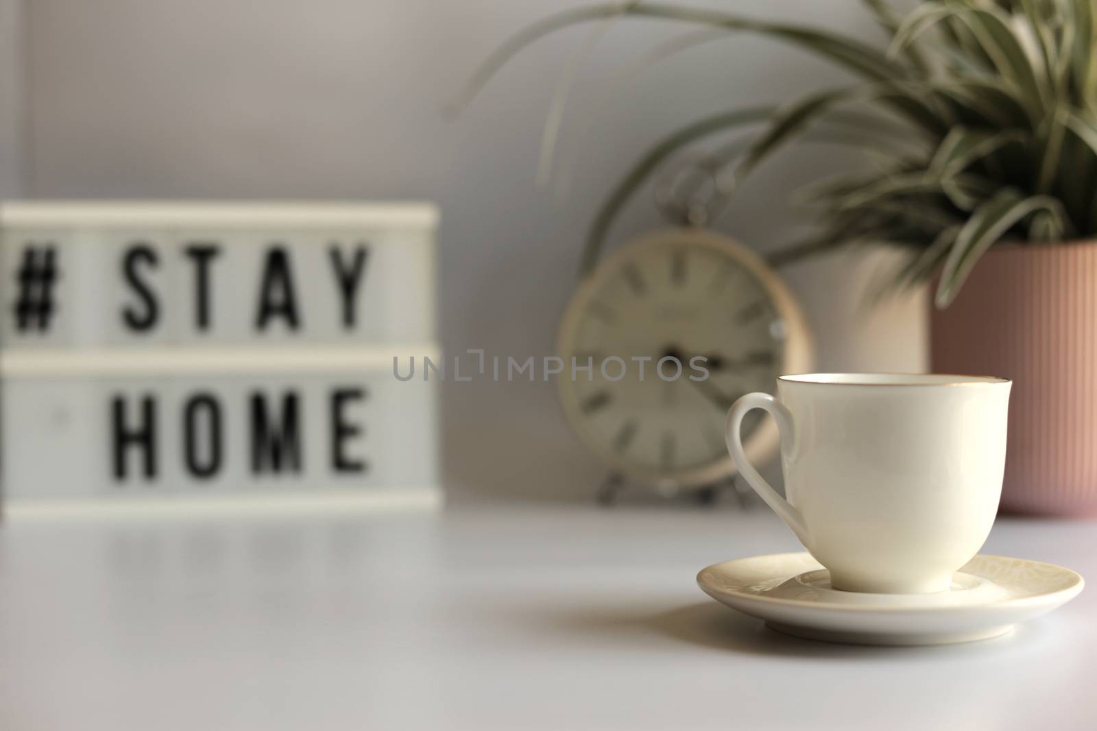 Home office desc concept during self quarantine as preventive measure against virus. Stay safe concept. Cup of coffee, clock, stationary, home plant on white background