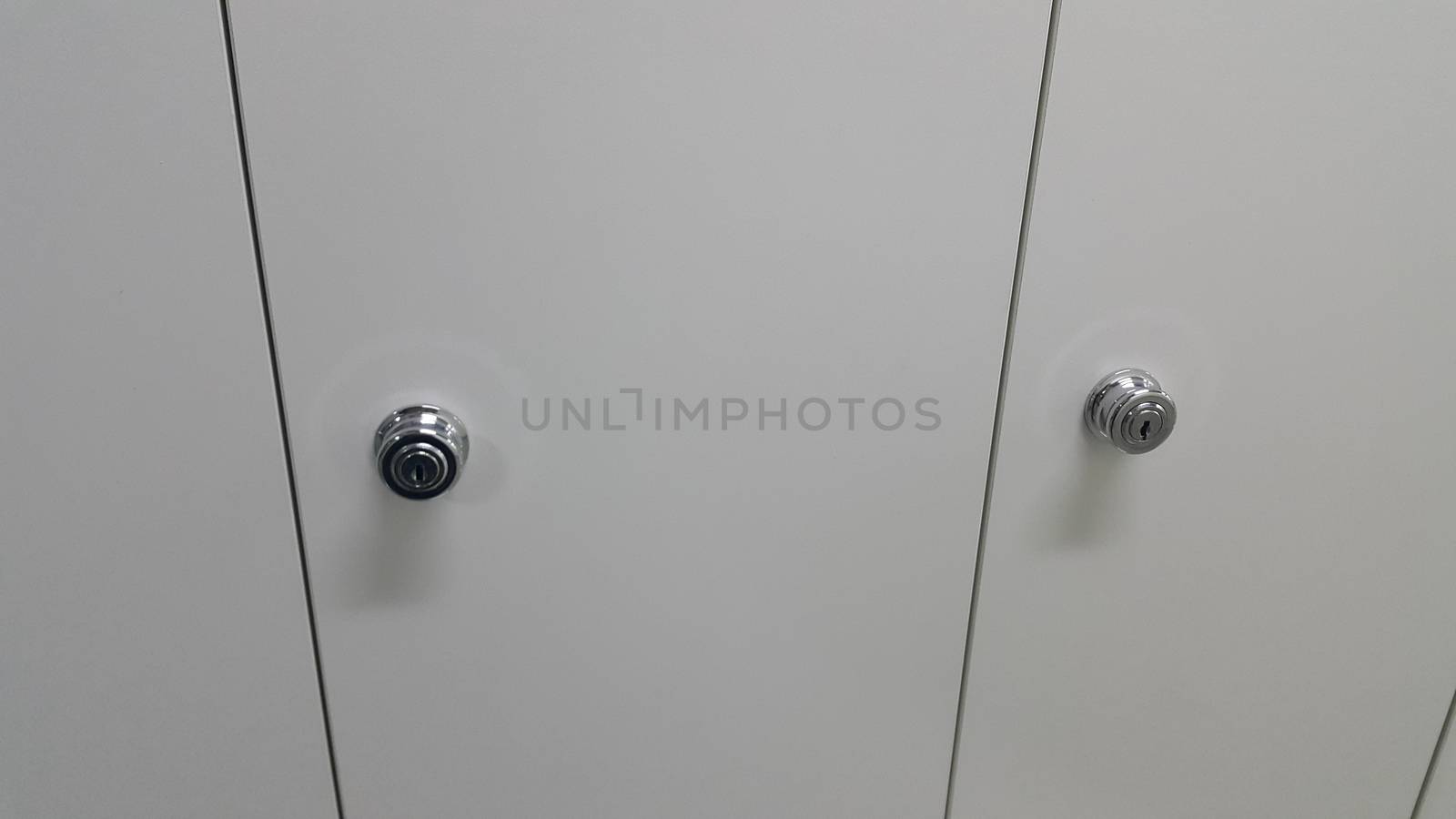 Perspective view of lockers or cupboards in a row with white doors, keys and locks