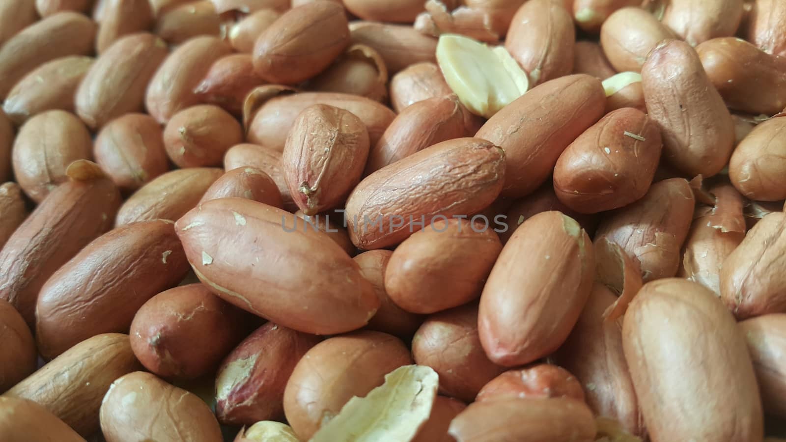 Closeup view of mixed, dried, roasted  peeled and unpeeled peanuts. A fruit for background text