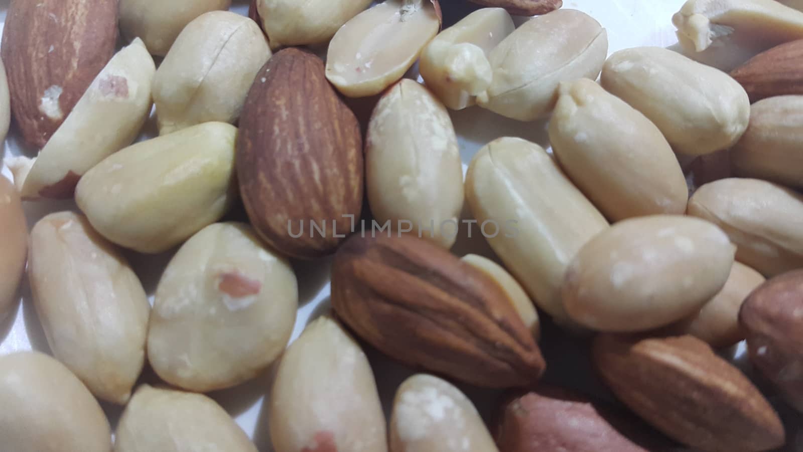 Closeup view of mixed dried and roasted  peanuts and almonds. A fruit for background text
