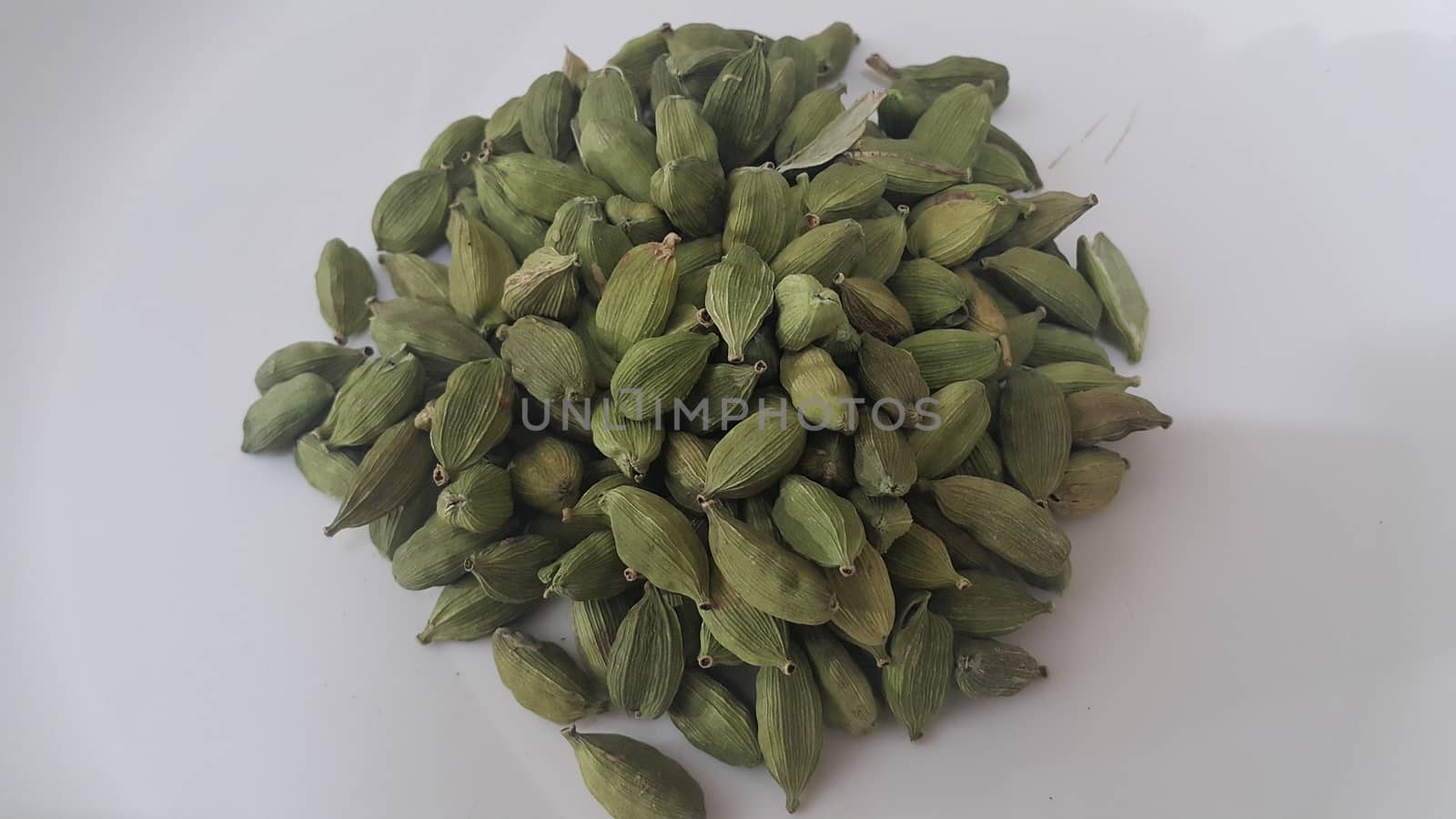 Closeup top view of dried green Elettaria cardamomum fruits with seeds, cardamom spice on white background