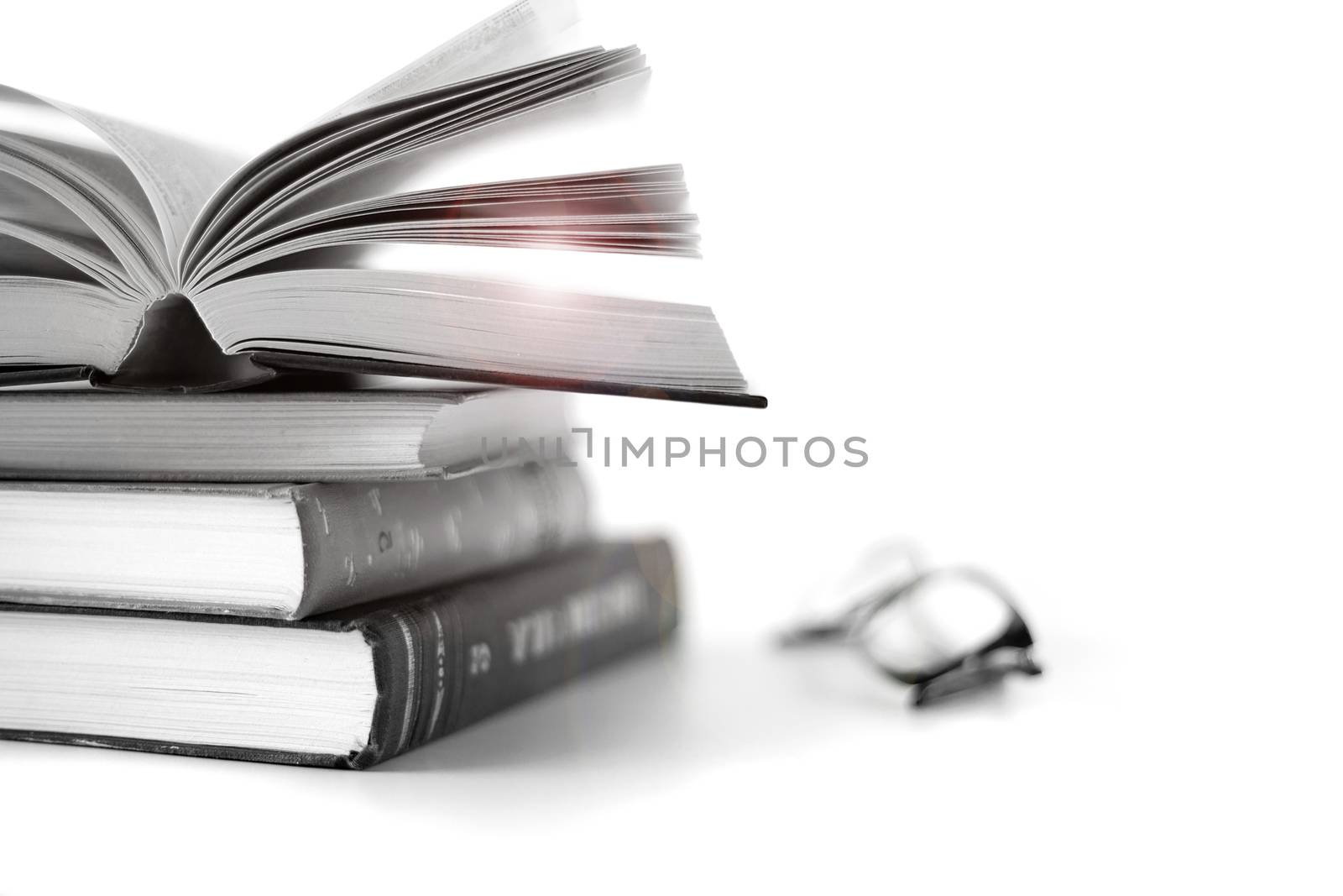 Open book on the pile of old books and reading glasses with light flare on white background. Self care, time away from technology, finding quiet place with book. Unplug yourself, finding time to calm the brain concept