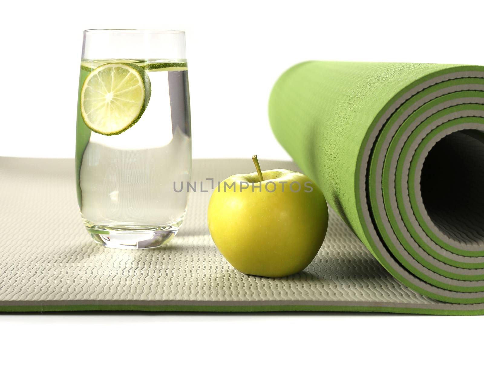 Green yoga mat with apple and glass of water with lemon on white background, Healthy life concept