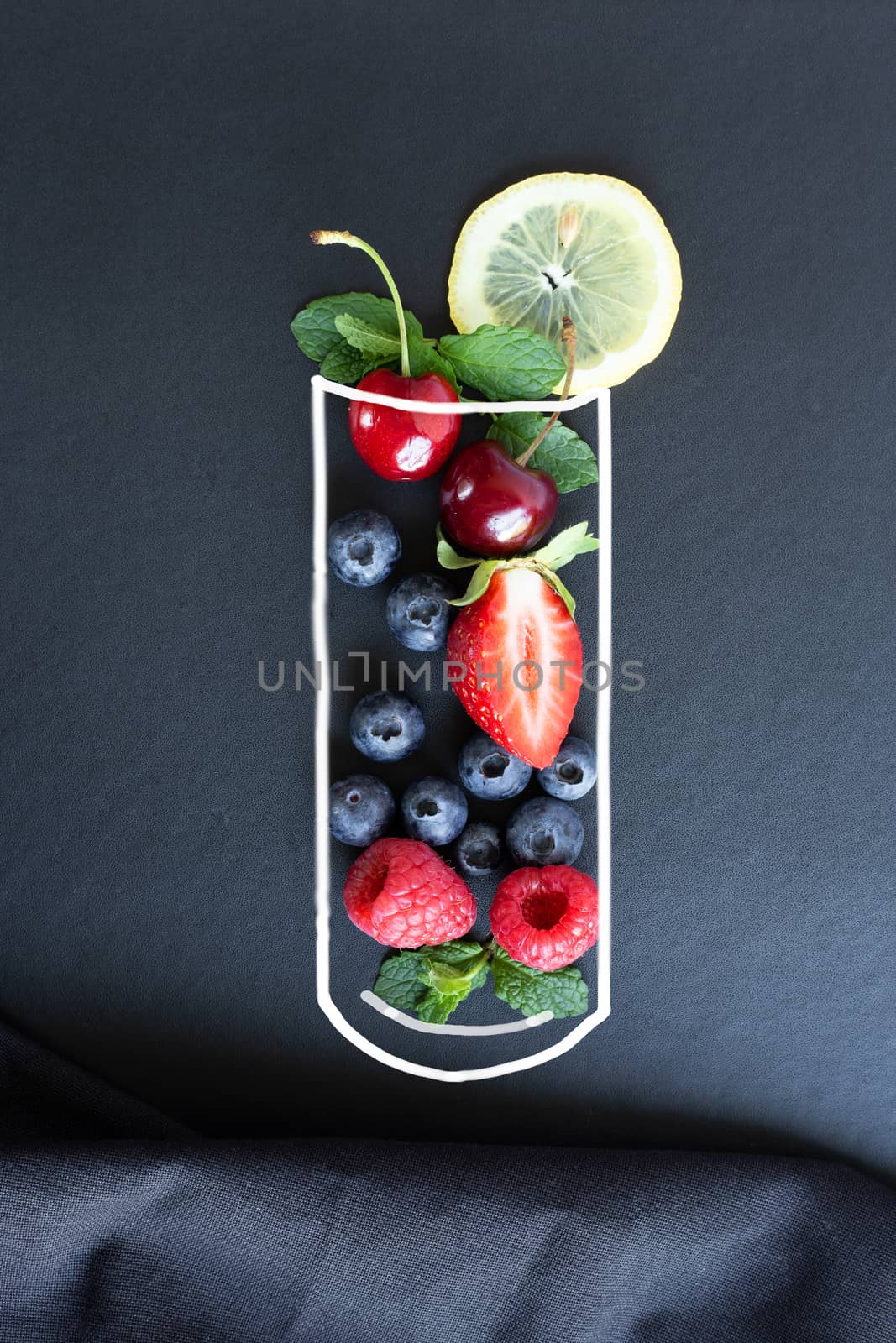Summer fruits, berries, lemon and mint in chalk painted glass of juice on black background with canvas. Conceptual healthy, vitamin, diettary food. Vegan, vegetarian and detox food and drinks. Menu mock up, poster concept
