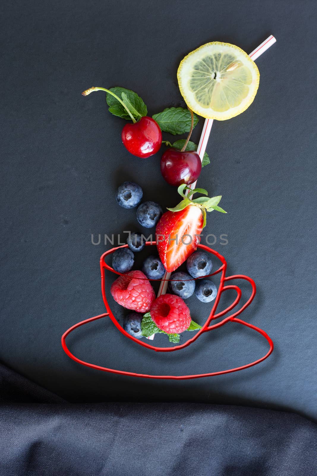 Summer fruits, berries and mint in chalk painted cup of tea with straw on black background with canvas. Conceptual healthy, vitamin, dietary food. Vegan, vegetarian and detox food and drinks. Menu mock up, poster concept