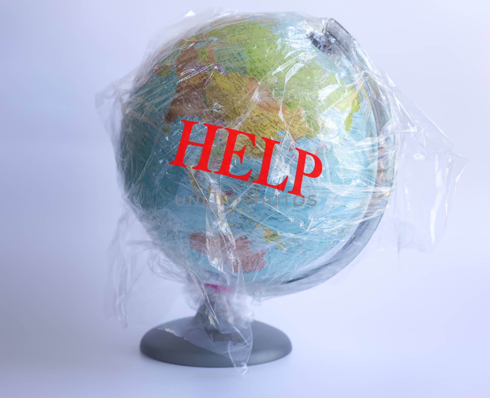 Text Help and model of planet Earth wrapped in polyethylene plastic disposable package on grey background. Ecology, plastic problems. Concept pollution of environment with polyethylene plastic waste World Earth Day, Save the planet
