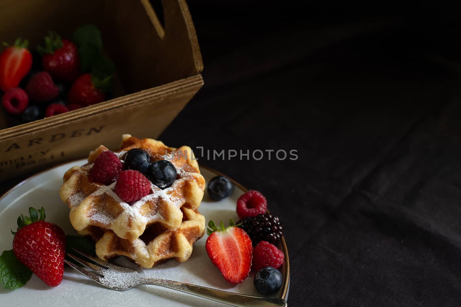 Belgian waffles with strawberries, summer berries on plate on dark old wooden dramatic background. Horizontal view. Menu, banner, poster, mock up. Rustic vintage style of kitchen.