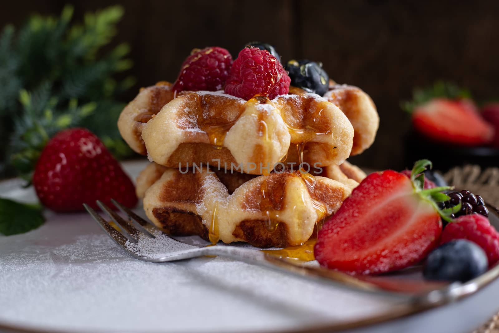 Belgian waffles with strawberries, summer berries on plate on dark old wooden dramatic background. Horizontal view. Menu, banner, poster, mock up. Rustic vintage style of kitchen.