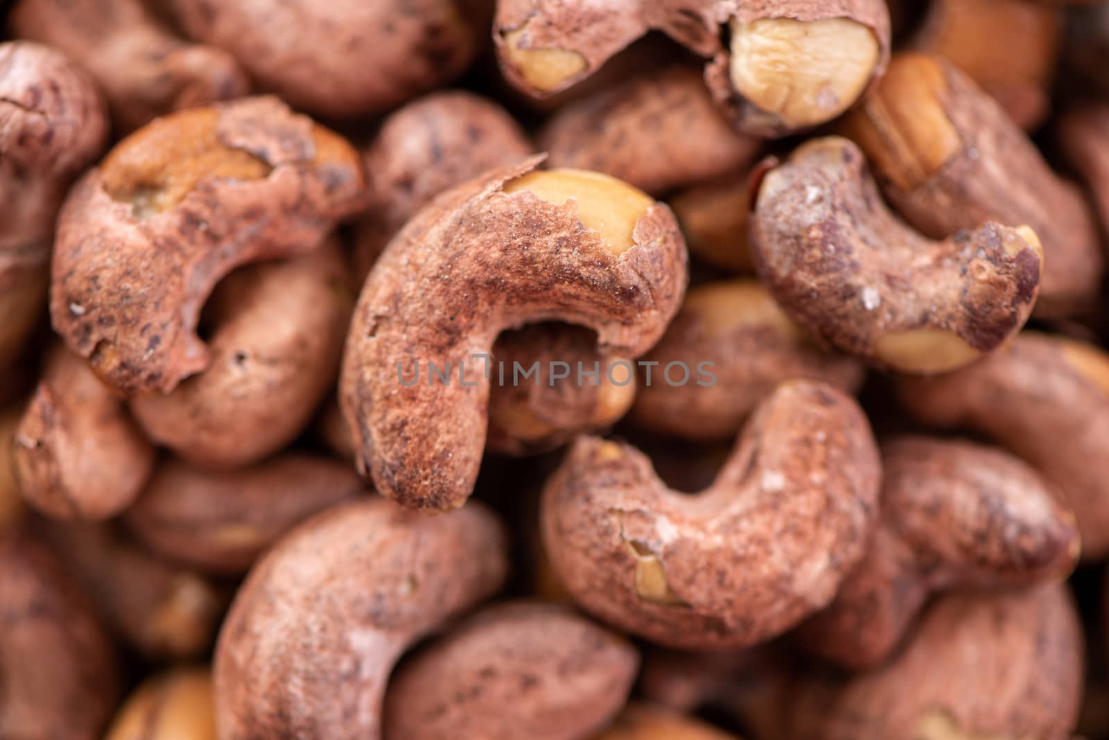 Cashew nuts with peel in a plate on wooden tray and table background, healthy raw food plate.