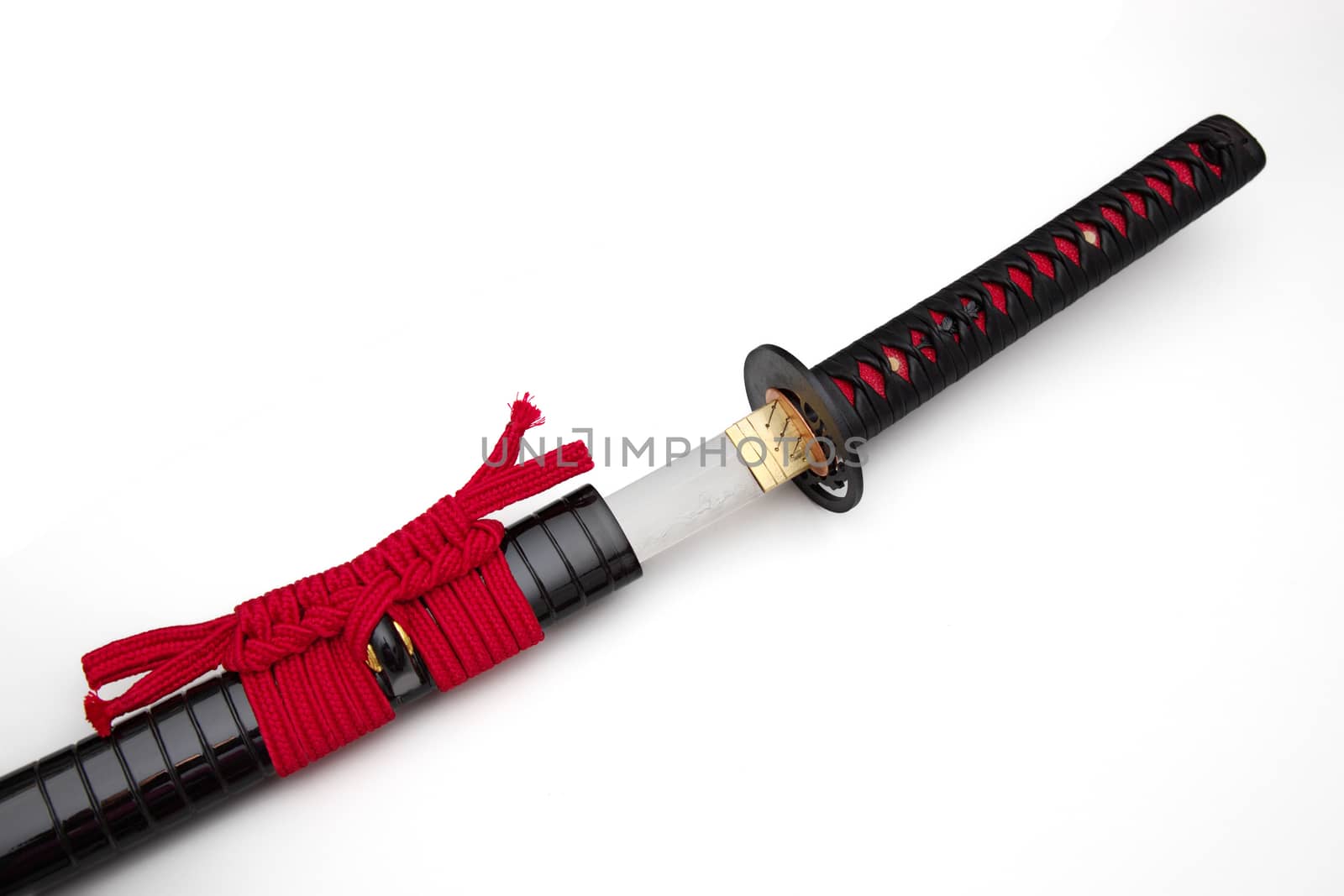 Japanese sword with red cord   steel fitting and shiny black scabbard on white background. Selective focus. by joker3753