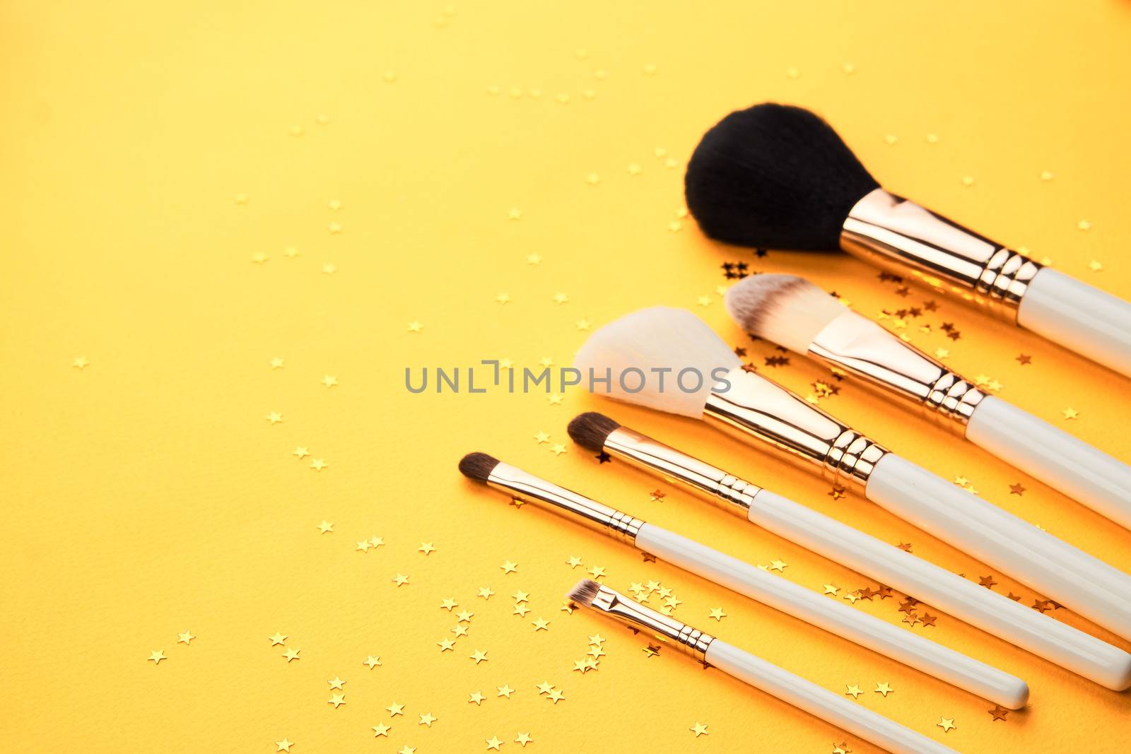 Makeup brushes on yellow background and sequins cropped view of Copy Space. High quality photo