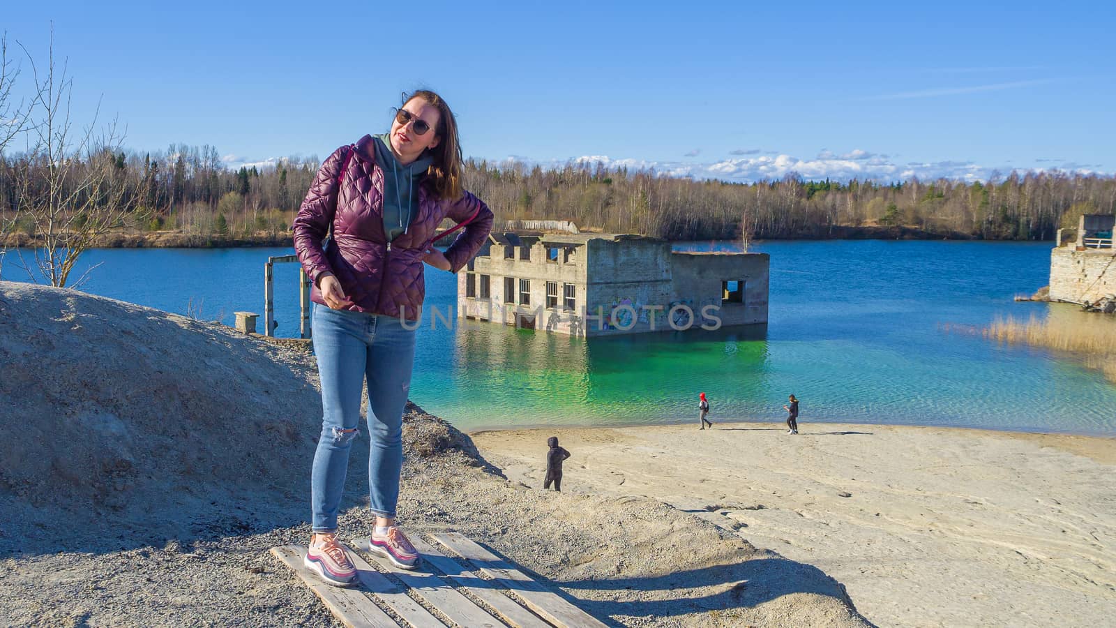 Hiker on mountain top. Woman is standing with an Abandoned Quarry and water on the background. Scenic View Of Land Against Clear Blue Sky. Panoramic View.