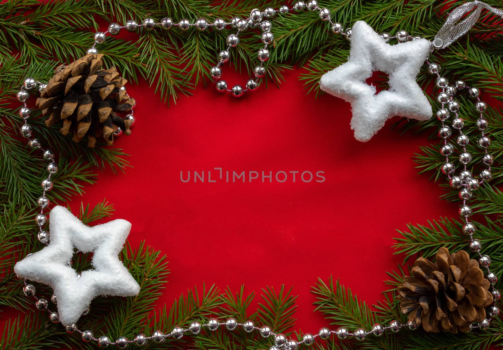 A frame of green fir branches ,two white stars and two cones with silver beads on a red background. The concept of Christmas and New year. Space for your text by lapushka62