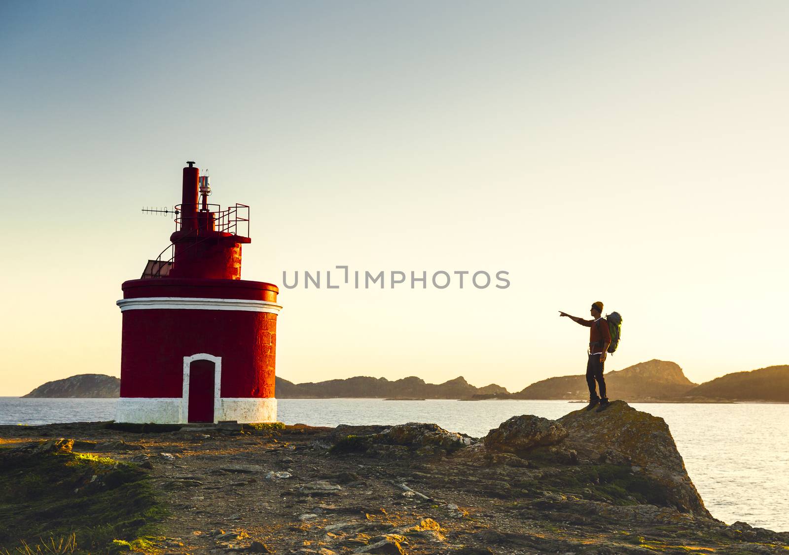 Man pointing to a beautiful ligthouse at sunset