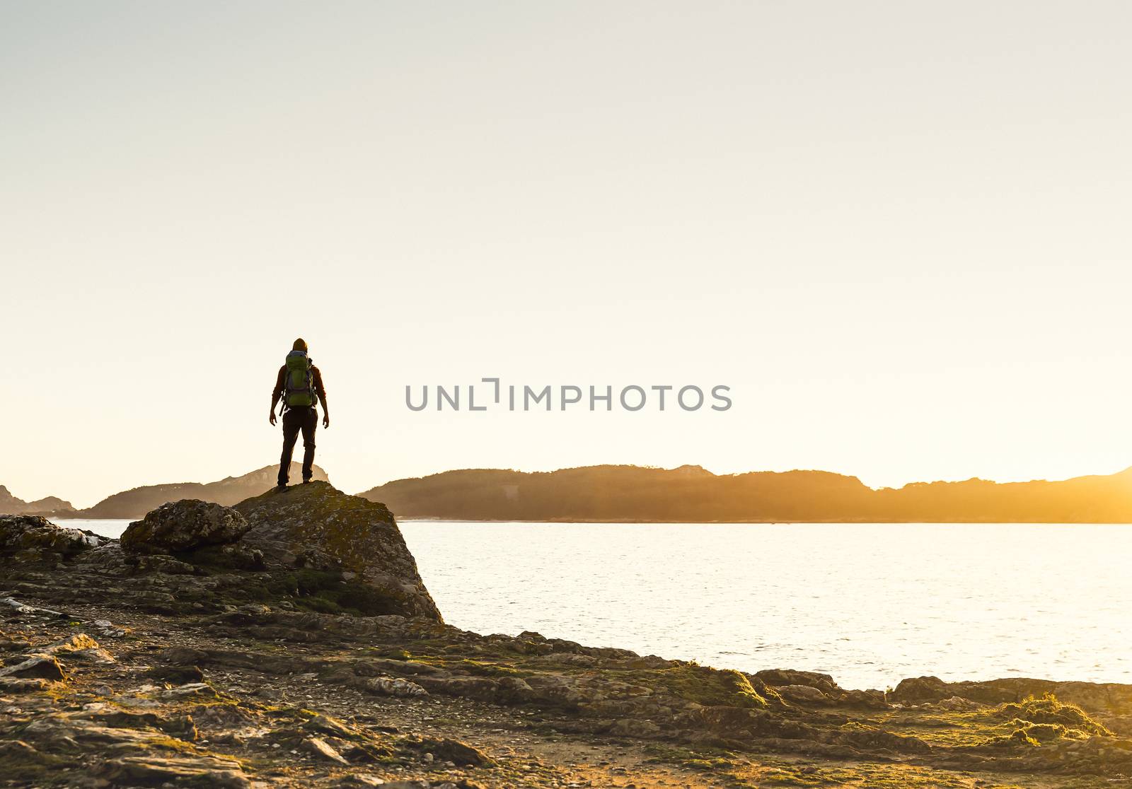 Man exploring the coast line at sunset by Iko
