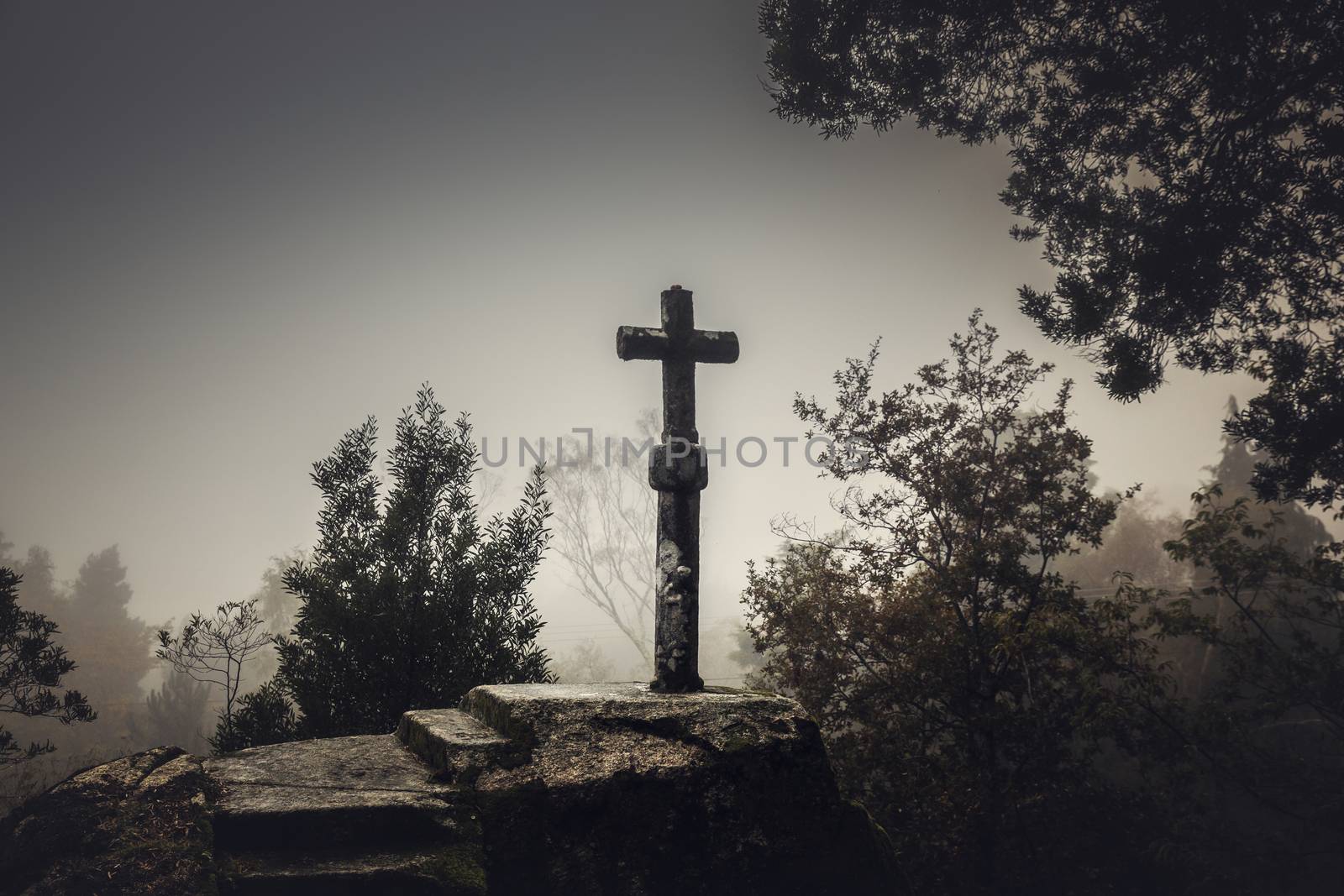 Shot of a beautiful religious stone cross on a foggy day