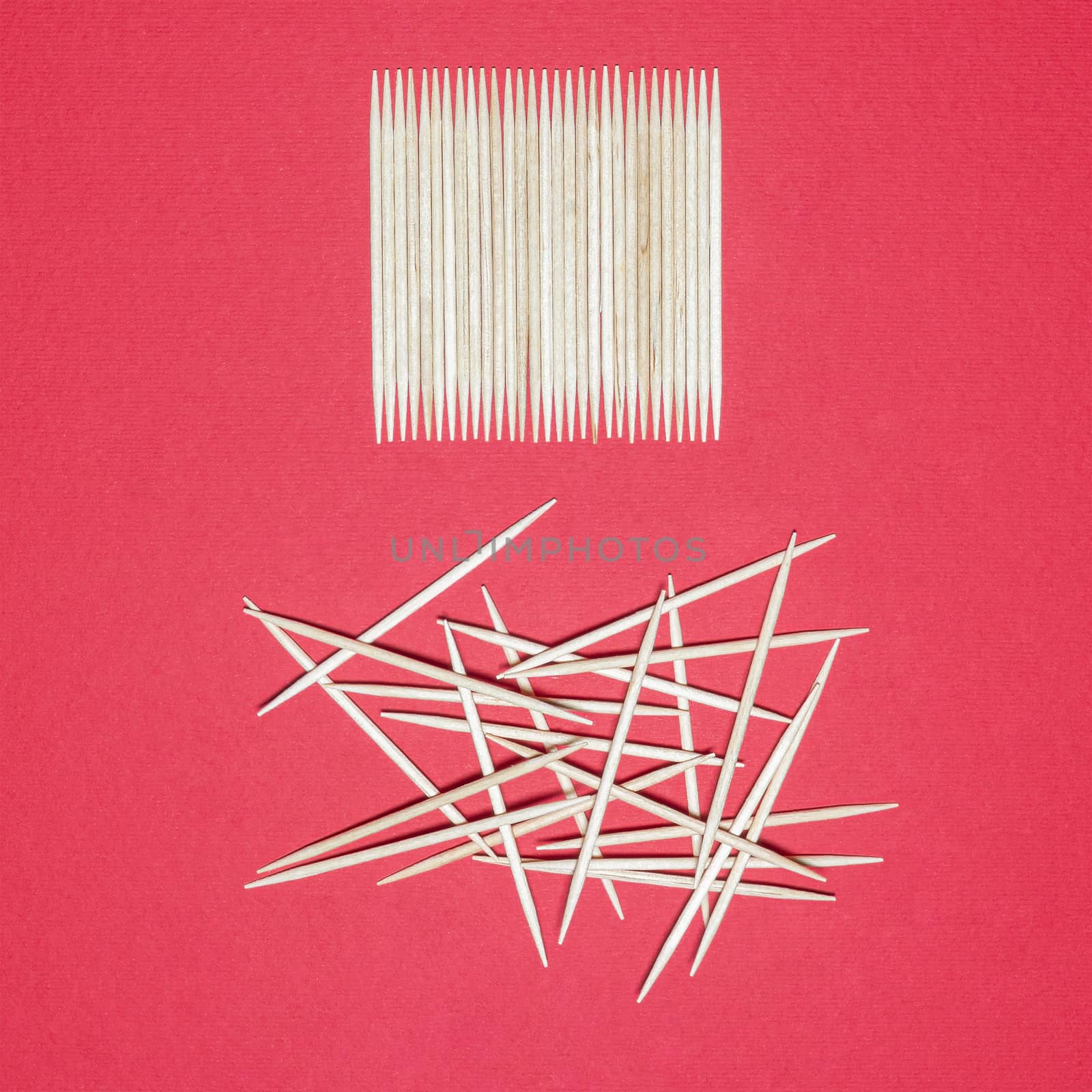 representation of order and disorder with toothpicks on a red surface