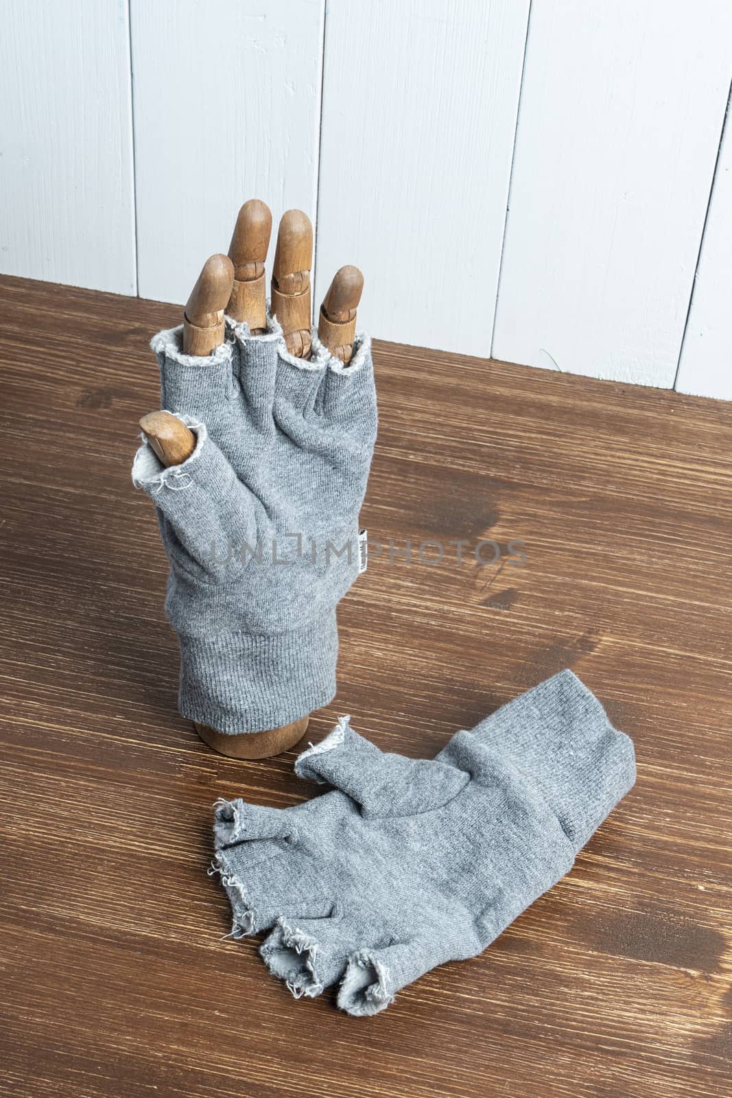a glove with cut fingers worn on a wooden hand on a table