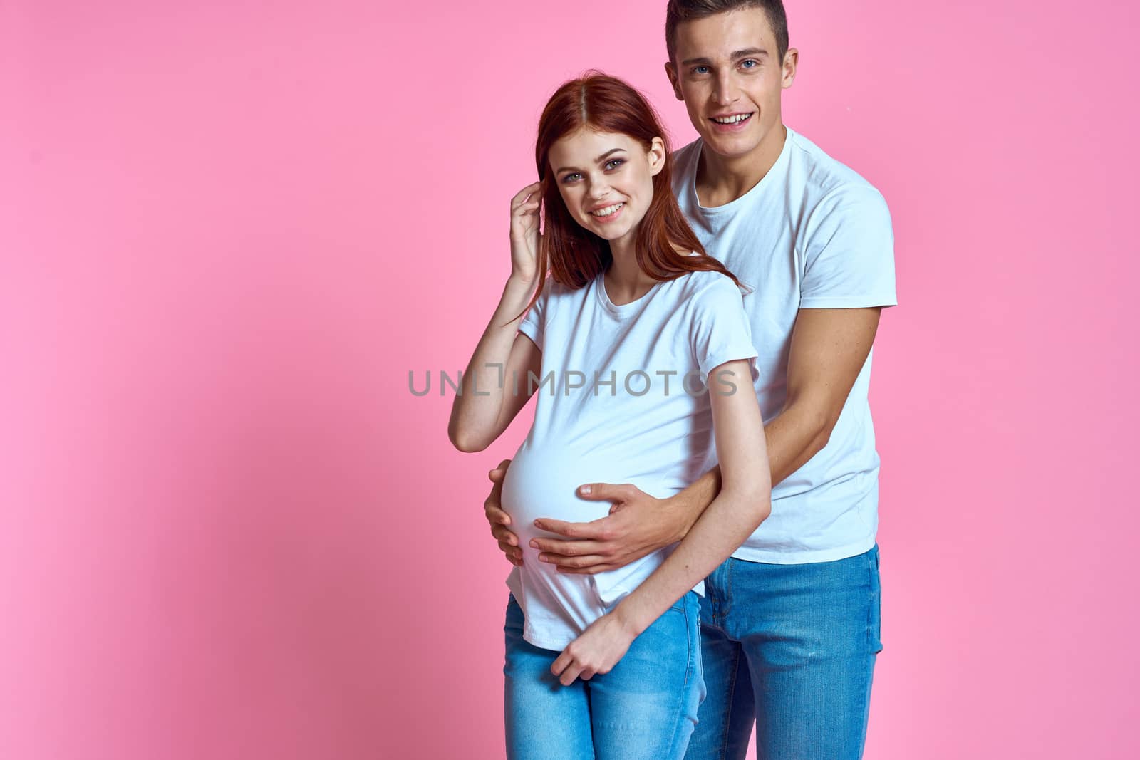 pregnant mom and happy father on pink background Young family waiting for baby. High quality photo