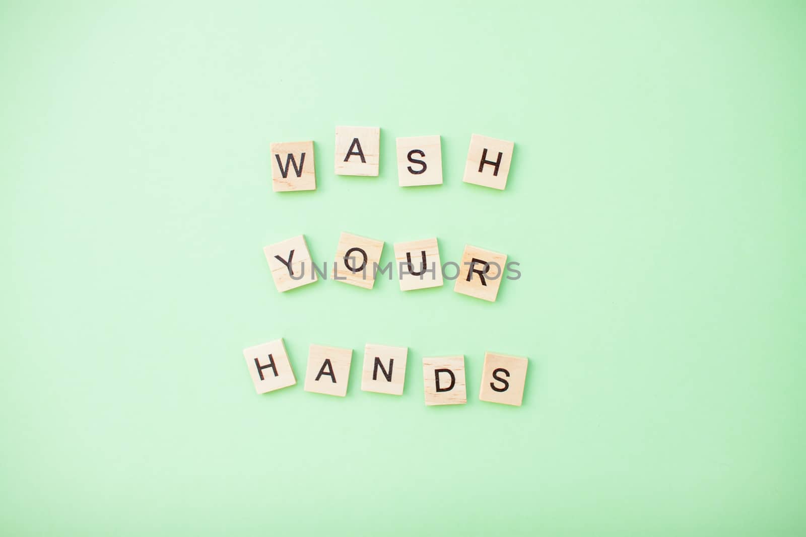 inscription from wooden blocks wash your hands on a light green background