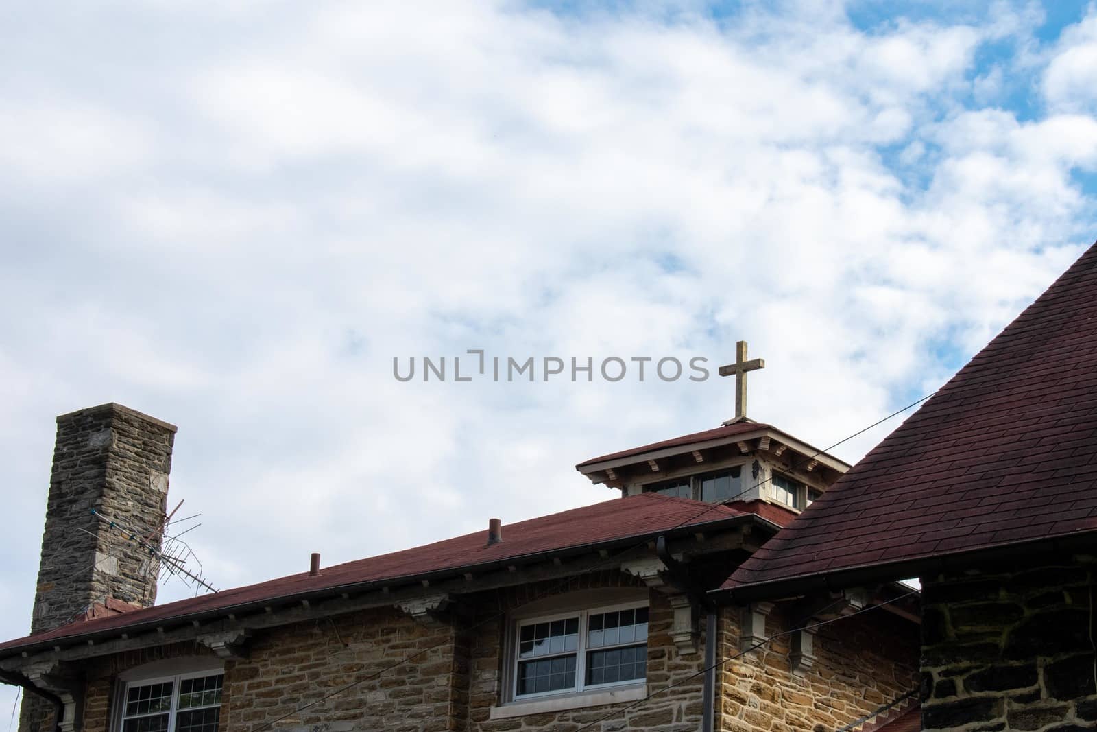 A Cross on the Roof of a Cobblestone Convent With a Cloudy Blue  by bju12290