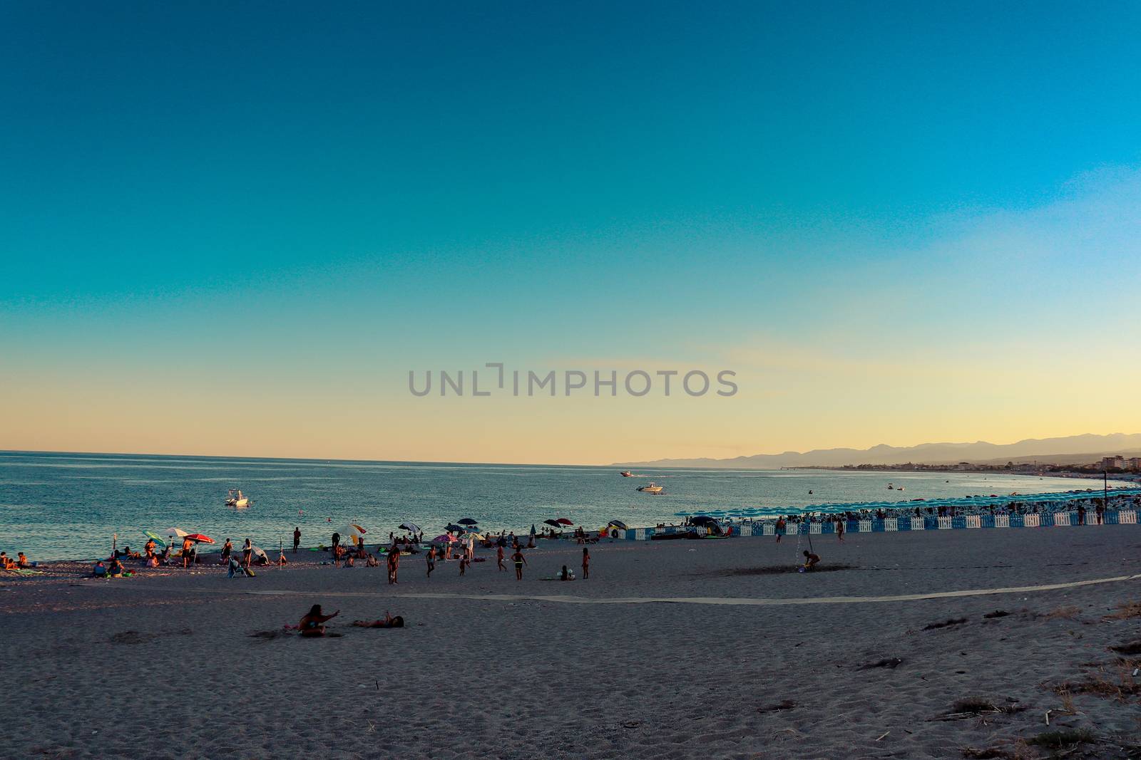 Italian beach with sea and people playing and bathing. Lido on a pebble beach. Blue sky with clear sea by Andreajk3