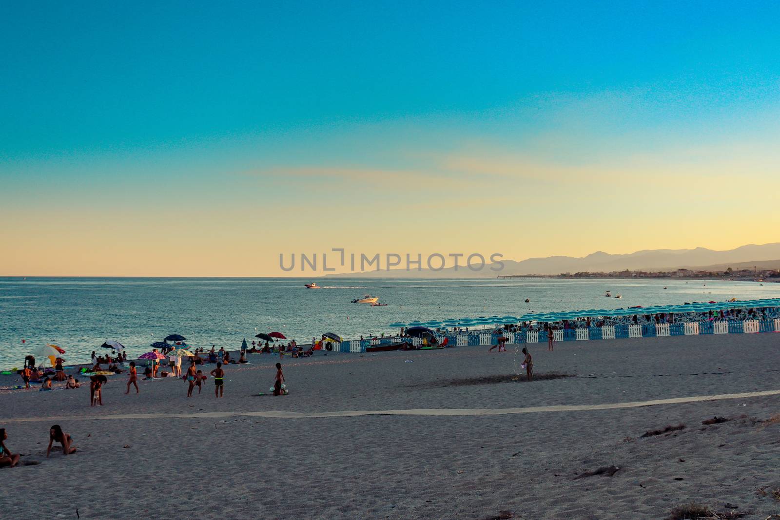 Italian beach with sea and people playing and bathing. Lido on a pebble beach. Blue sky with clear sea by Andreajk3