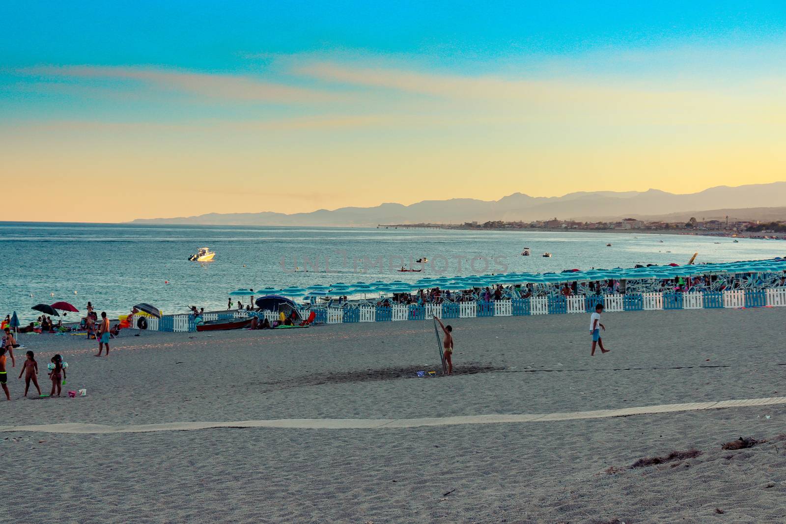 Italian beach with sea and people playing and bathing. Lido on a pebble beach. Blue sky with clear sea by Andreajk3