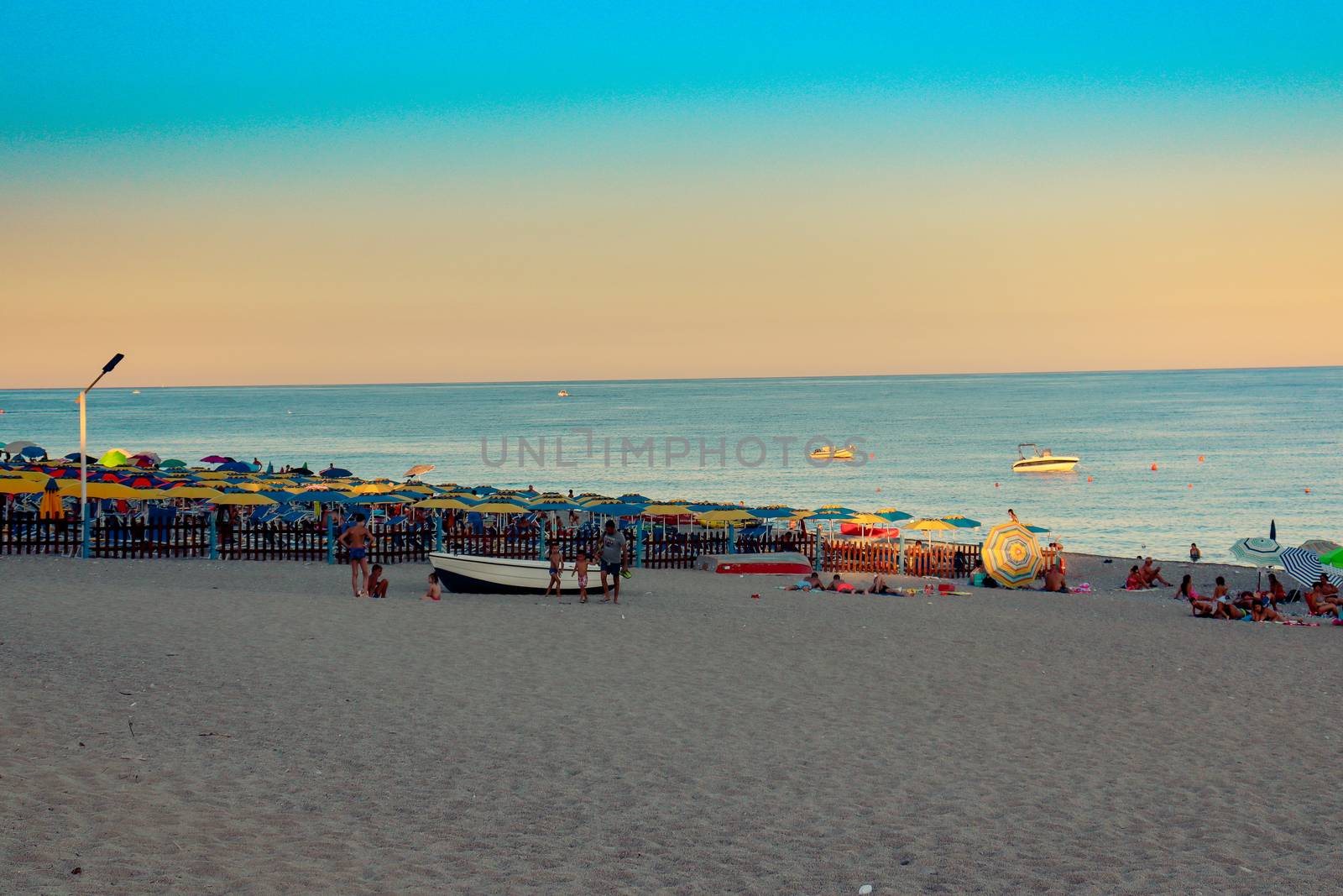 Italian beach with sea and people playing and bathing. Lido on a pebble beach. Blue sky with clear sea by Andreajk3