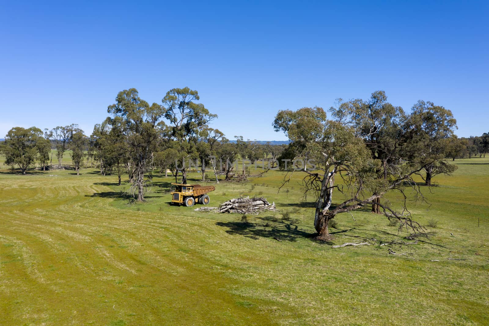 An aerial view of an old earthmoving truck in a lush green agricultural valley in regional Australia