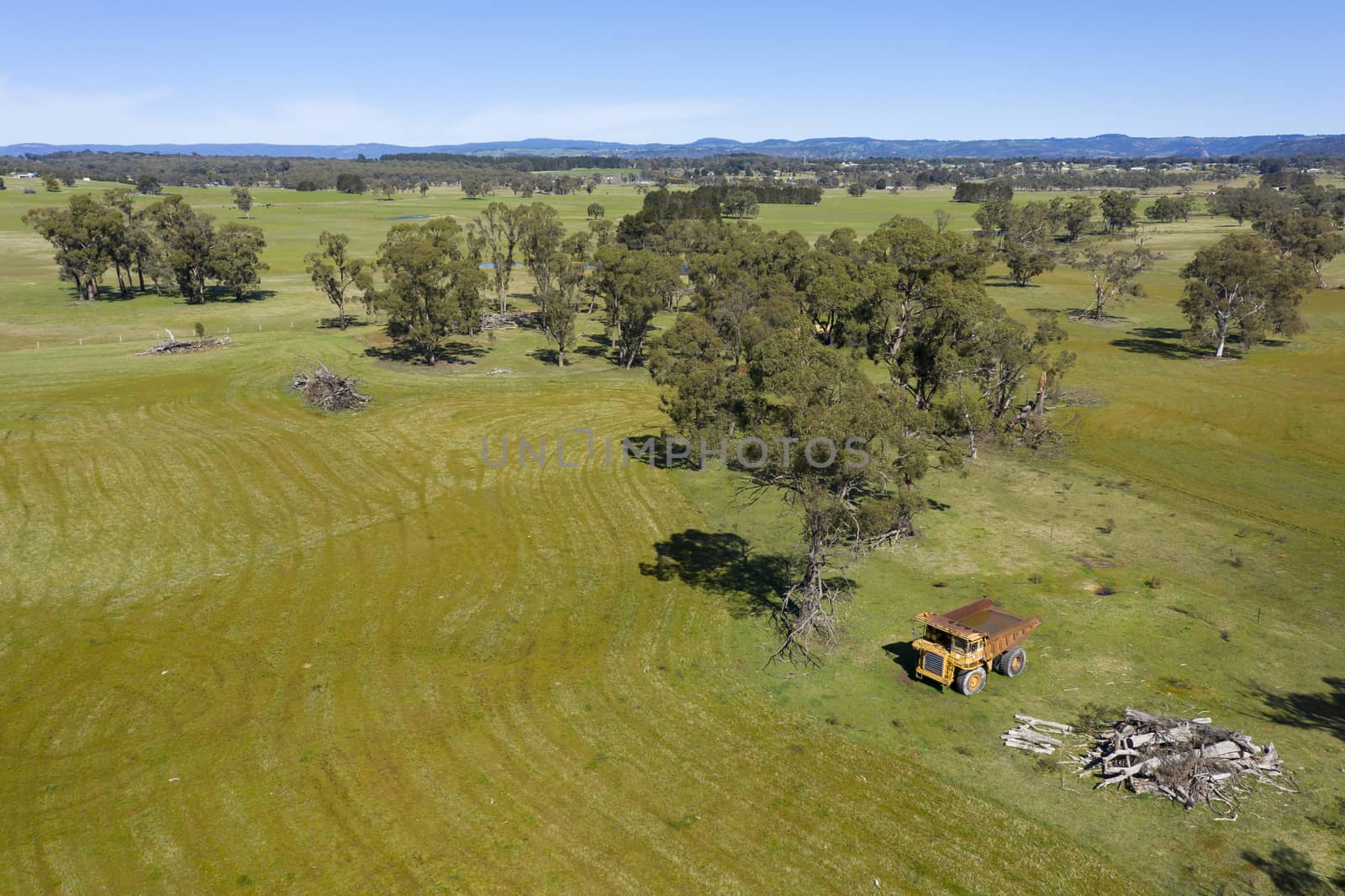 An aerial view of an old earthmoving truck in a lush green agricultural valley in regional Australia